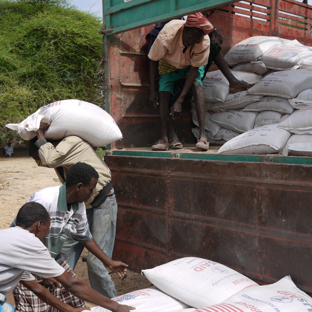 People in Africa unload USAID food shipments from the back of a truck